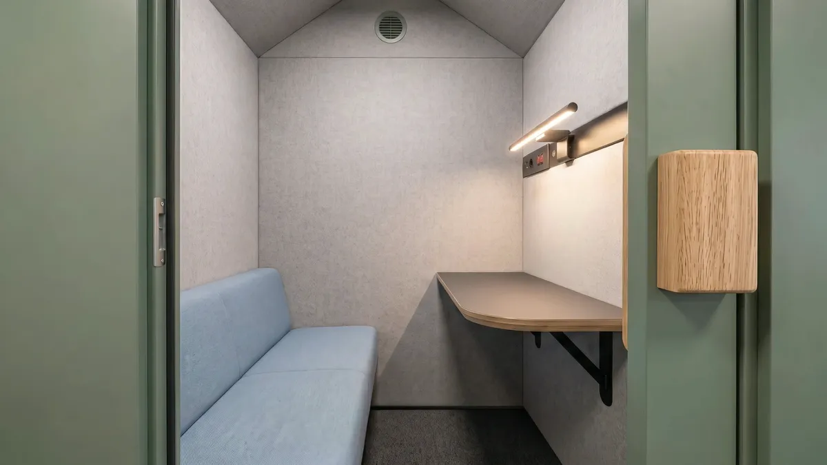 Vy från tröskeln in i Lillstugan: soffan till vänster, bordsskivan med uttagspanel och LED-list till höger