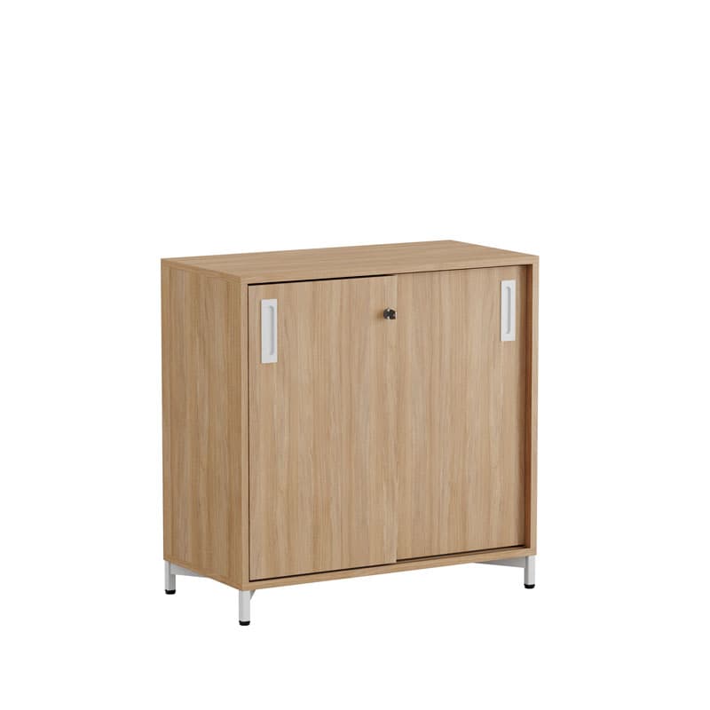 Lågt skåp i ljus ek med två skjutdörrar, låsvred och benställning i metall, sett snett framifrån mot vit bakgrund